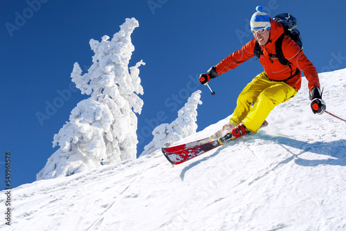 Skier skiing downhill in high mountains against against the fairytale winter forest.