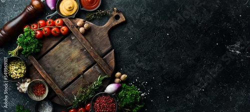 Obraz  z motywem Stone black cooking background. Kitchen board with vegetables and spices. On a black stone background. Top view.