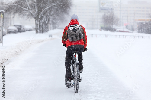 A man rides a bike on a winter path, rear view