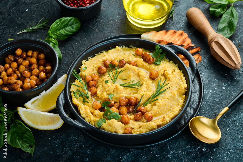 Traditional vegetarian hummus with chickpeas in a bowl. Top view. On a black stone background.
