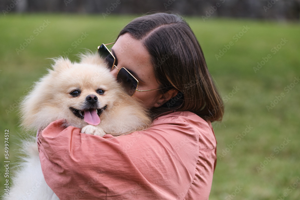 Girl hugging her pomeranian dog in a park. Girl hugging her pomeranian dog in a park.
