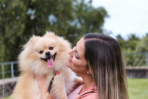 Portrait of a girl posing with her pomeranian dog in a park. Dog with its tongue out