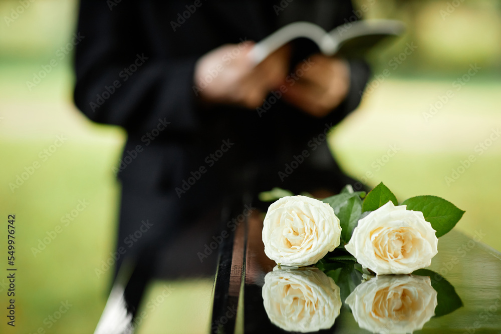 Naklejka premium Closeup of two white roses on coffin at outdoor funeral ceremony, copy space