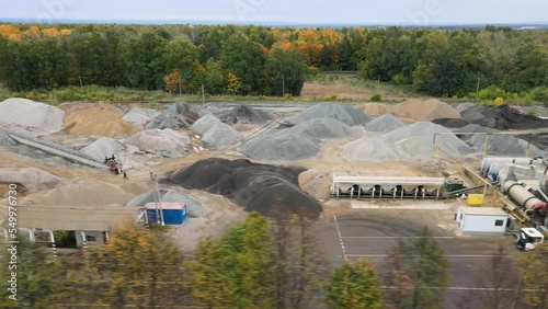 Bird's eye view of the construction site of mobile asphalt plant. Production of asphalt concrete. Heaps of rubble, sand and bitumen. Heavy construction equipment at work. Modern building technologies