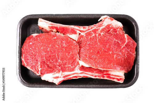 Raw ribeye beef steak ready for grilling in black food container isolated on white