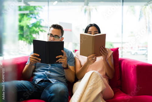 Reader couple enjoying a book while relaxing on the couch
