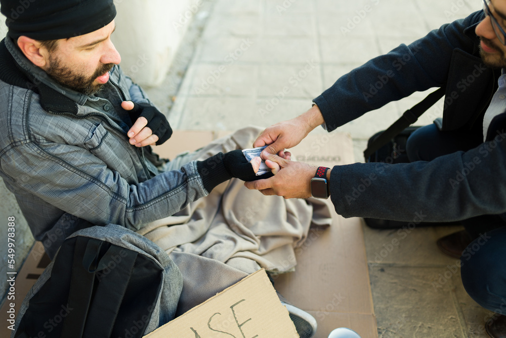 Fototapeta premium Concerned kind man giving money for food to a poor homeless man