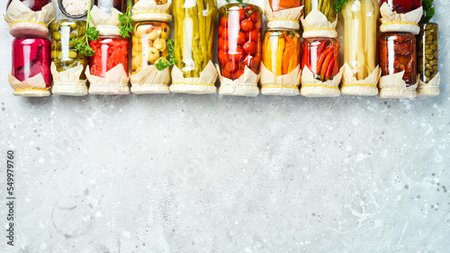 Jars with various pickled vegetables on a stone background. On a stone background. Top view.