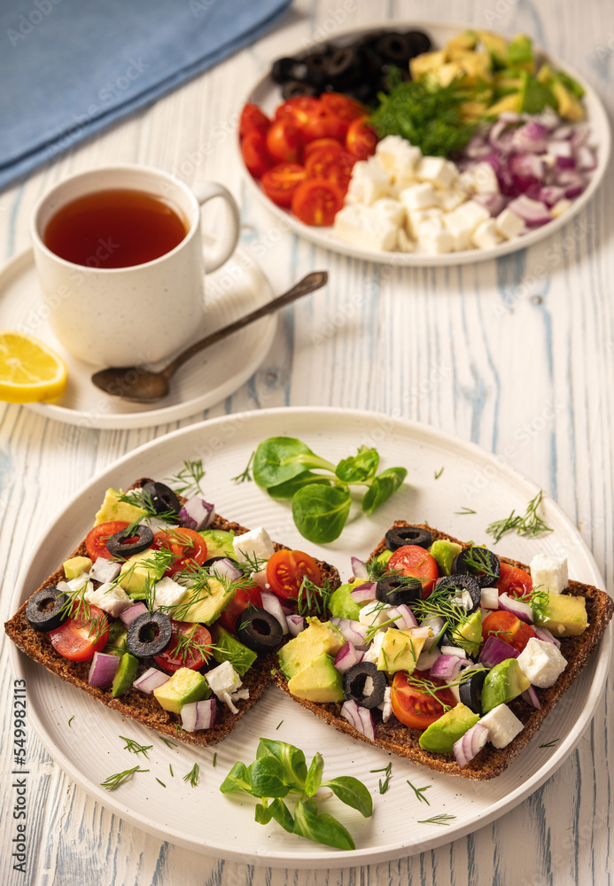 Tasty and healthy avocado, olives, cherry tomatoes and feta cheese sandwiches. Toasts with avocado, tomatoes and feta cheese. Tasty and healthy avocado, olives, cherry tomatoes and feta cheese sandwiches. Toasts with avocado, tomatoes and feta cheese.