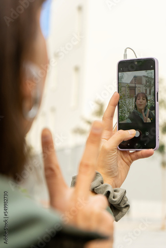 happy girl. Hand of a girl holding the cell phone while she takes a selfie in a park