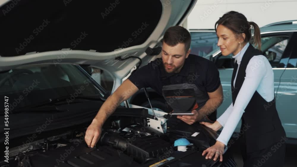 A neat car master conducts the first inspection of the car in the presence of the woman who owns the car A neat car master conducts the first inspection of the car in the presence of the woman who owns the car