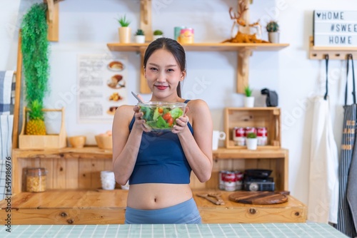 Young beautiful asian female adult lady in gym outfit after yoga exercise. Eat clean food salad with tomato for healthy and slim fit lifestyle.