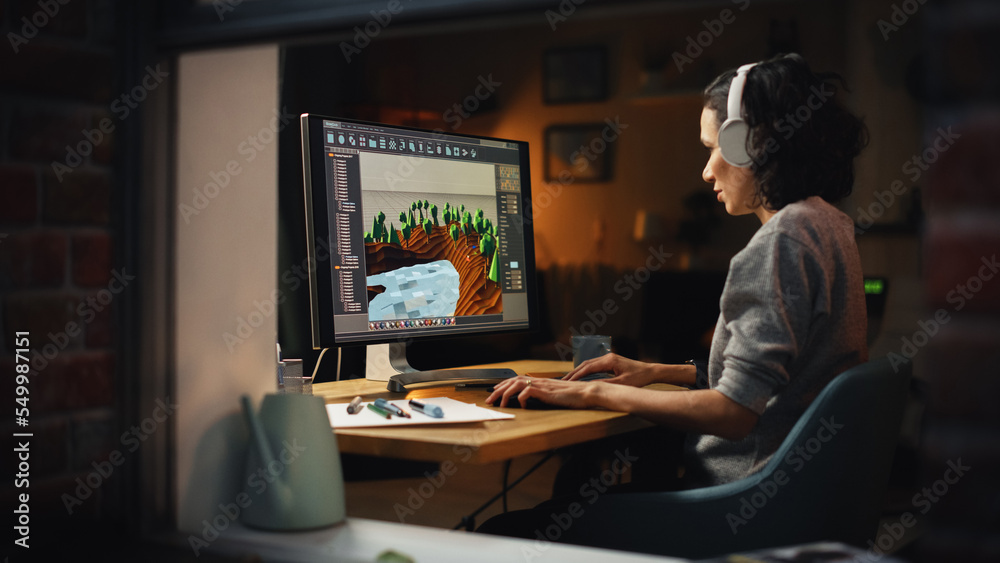 Female Video Game Designer Works on a New 3D Level on Personal Computer. Focused Woman Creating Metaverse and Design Video Game. Shot Into the Apartment Window Late at Night. Female Video Game Designer Works on a New 3D Level on Personal Computer. Focused Woman Creating Metaverse and Design Video Game. Shot Into the Apartment Window Late at Night.