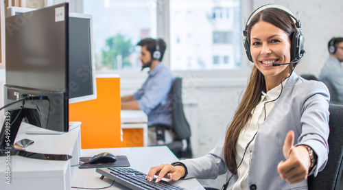 Foto Portrait of beautiful young woman wearing headset showing thumbs up gesture