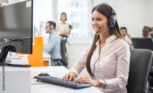 Smiling female helpline operator with headset in call center. photo