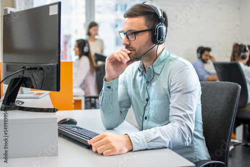 Customer service support operator man with headphones and microphone listening to his client in call center.