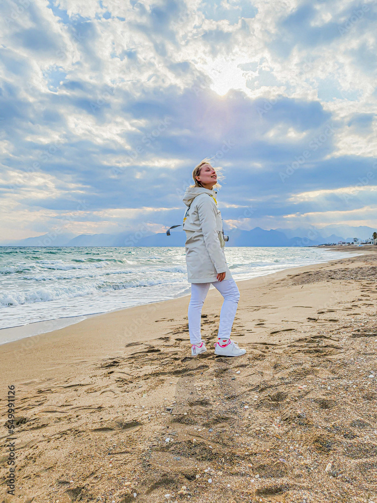 Girl in a white jacket on the background of the sea. Freedom.