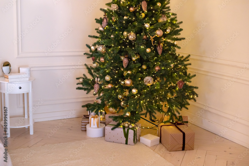 Fototapeta premium Festive interior design living room with a Christmas tree and decorations. Xmas at home. New year winter home decor. Christmas tree with lights glowing garlands and gifts. 