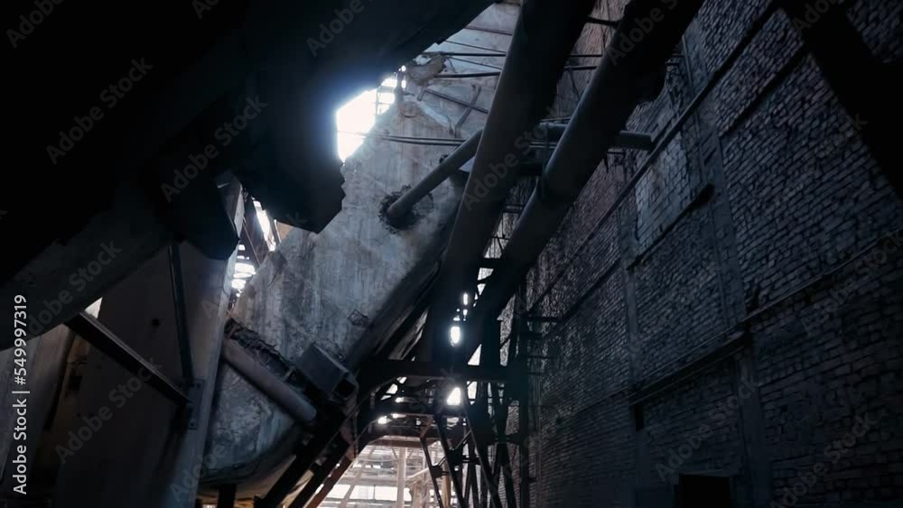 Scary dark ruins of an old abandoned factory. Brick wall and rusty pipes and metal structures of a coal-fired power plant. Scary dark ruins of an old abandoned factory. Brick wall and rusty pipes and metal structures of a coal-fired power plant.