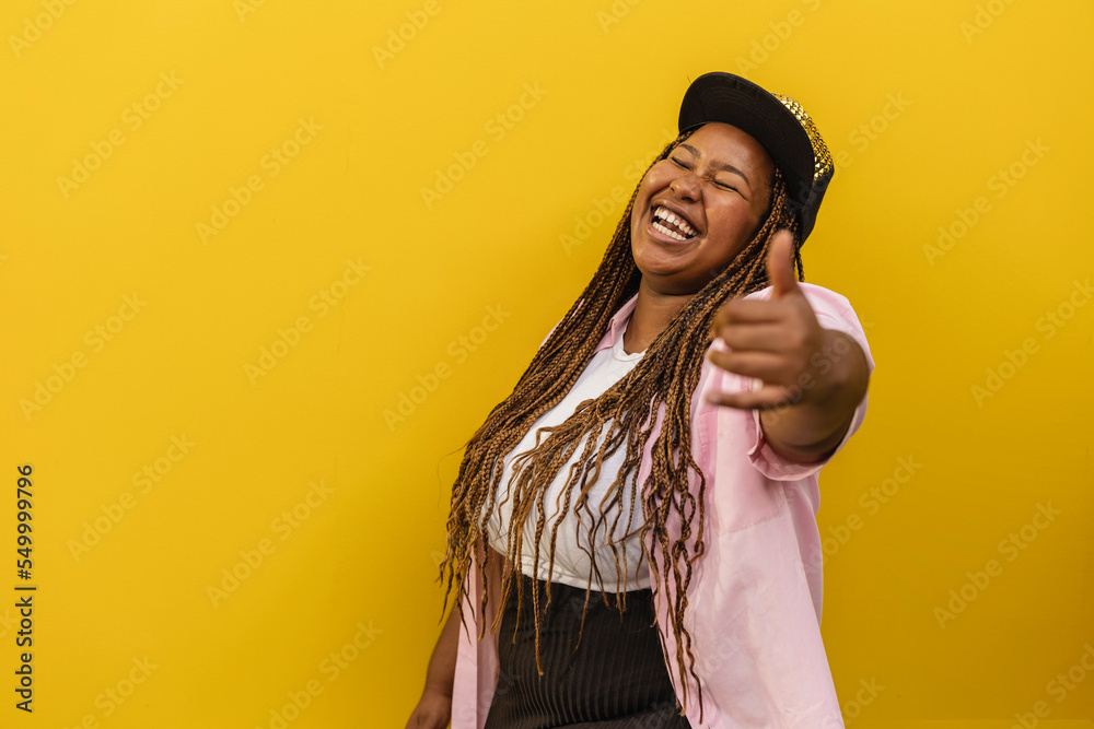 Cheerful woman laughing and gesturing in front of yellow wall Cheerful woman laughing and gesturing in front of yellow wall