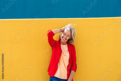 Happy woman with hand in hair wearing red blazer photo