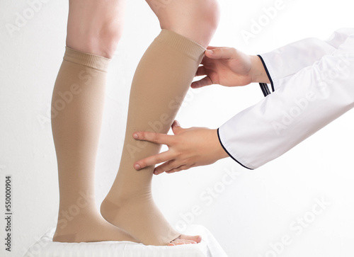 The phlebologist doctor selects the size of the patient's compression stockings. White background, close-up.
