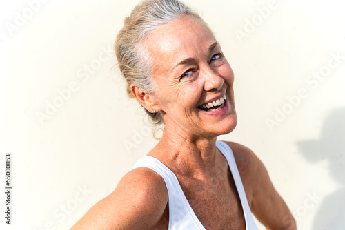 Happy mature woman in front of cream colored wall photo