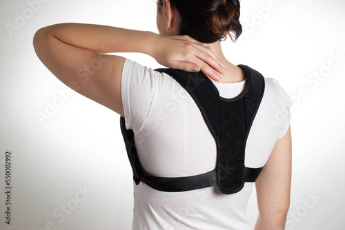 Woman in black posture corrector and fixation brace for the thoracic spine, close-up. Treatment of chronic back pain, osteochondrosis, orthopedic corset photo