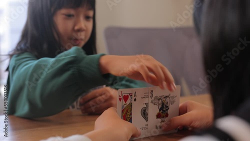 Asian teenage girl playing cards. Old Maid. Pick up joker.