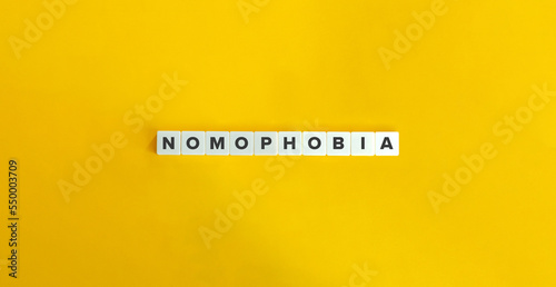 Nomophobia Word and Banner. The Fear of Being Without Your Phone. Letter Tiles on Yellow Background. Minimalist Aesthetics.