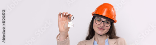 A girl in a construction helmet holds a house. Realtor on a white background.