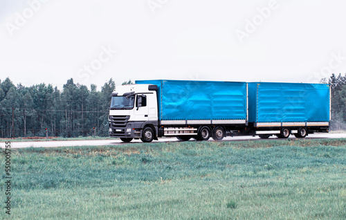 Truck tractor hitch with semi-trailer transports cargo on a country highway with a large tonnage and volume of cargo. Copy space for text. Industry