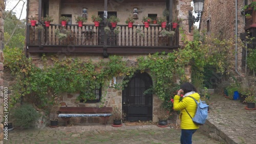 Young woman walking in front of a house in one of the most beautiful villages in Spain, Barcena Mayor, Cantabria.