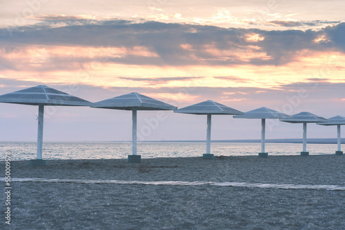 Beach umbrellas on the desert coast of the sea at sunset.