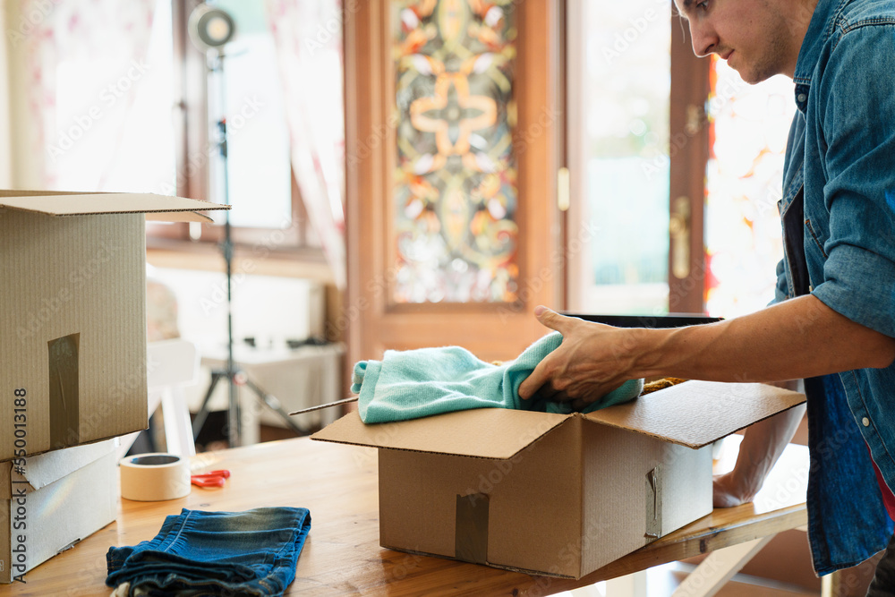 Man packing clothes inside box, concept of clothes donation. Man packing clothes inside box, concept of clothes donation.