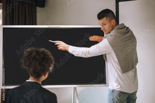 Man pointing with hands near blackboard looking at woman