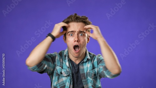 Handsome thinking young man 20s, looks at camera gives mind blown gesture showing explosion of ideas posing on purple background.