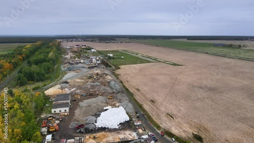 Bird's-eye view of the territory of the asphalt plant between two highways. Trucks are loaded with sand, gravel and bitumen. Picturesque cinematic industrial landscape. Large-scale construction work