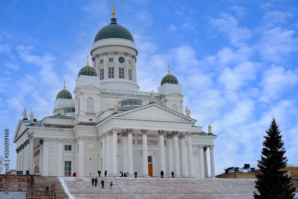 view of Helsinki Cathedral of St. Nicholas on Senate Square, people walking along winter street, decorated Christmas tree, concept holiday, pre-holiday chores citizens, tourists Finland