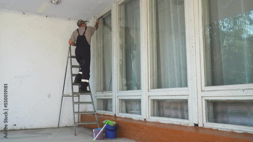 A man window cleaner cleans a window with a silicone or rubber scraper