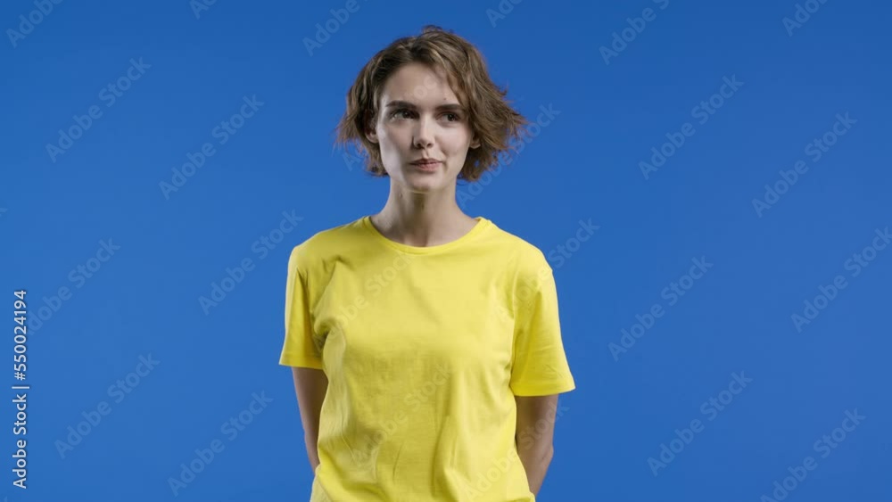 Beautiful woman in yellow wear on blue background. Young lady looking to camera. Short trendy hairstyle, cheerful smile. Beautiful woman in yellow wear on blue background. Young lady looking to camera. Short trendy hairstyle, cheerful smile.