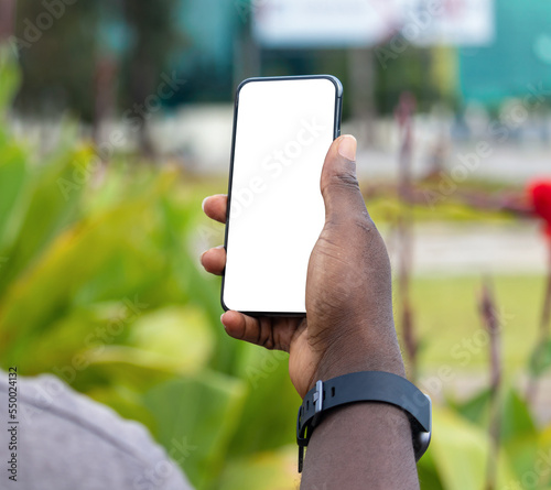 Main d'un jeune homme noir africain tenant un smartphone écran vierge blanc photo