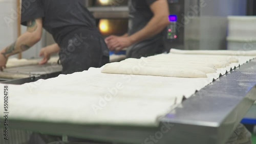 tattooed baker kneading bread doughs and placing the doughs with flour on the workbench of the bread workshop