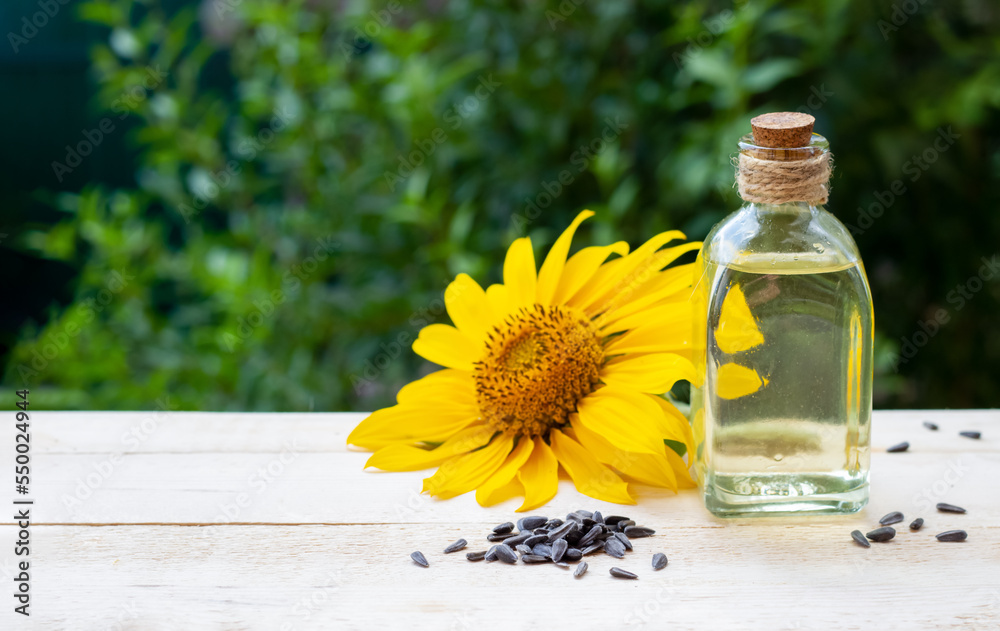 Close-up of sunflower oil in a bottle glass with seeds and sunflower Close-up of sunflower oil in a bottle glass with seeds and sunflower
