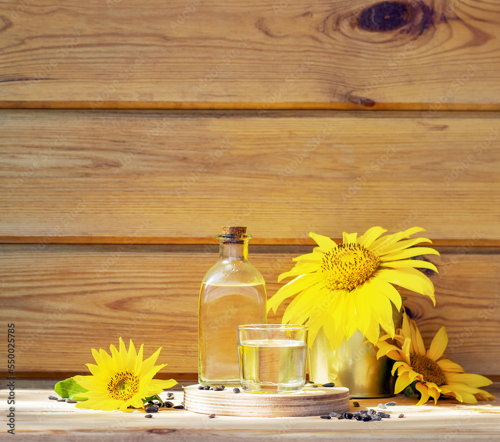 Sunflower oil in a bottle glass with seeds and sunflower on wooden background Sunflower oil in a bottle glass with seeds and sunflower on wooden background