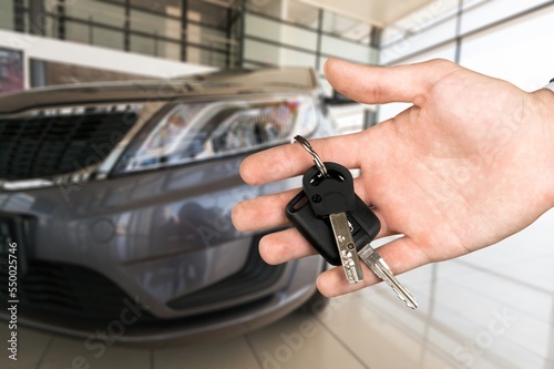 Hand hold a new car key on car background