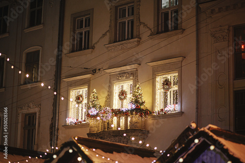 Stylish christmas festive lights, trees and wreath decor on balcony in evening. Modern christmas decor in city street. Atmospheric winter holidays in Europe. Merry Christmas and Happy Holidays © sonyachny