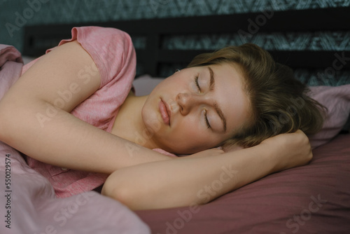 Woman sleeping. Beautiful young woman lies with her eyes closed in bed covered with blanket