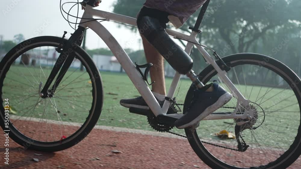 A disabled amputee cyclist riding bicycle with prosthetic leg. Determination and motivation concept A disabled amputee cyclist riding bicycle with prosthetic leg. Determination and motivation concept