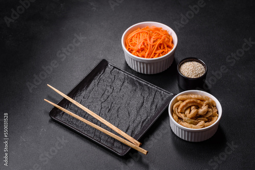 Tasty spicy Korean carrot with spices and herbs on a dark concrete background